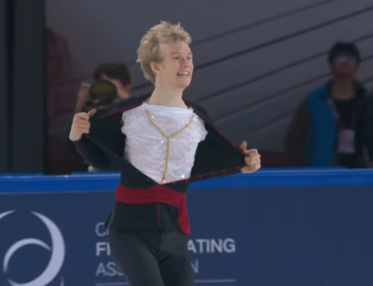 Figure skater Daniel Grassl mid-costume reveal from Cardinal to Pope. 