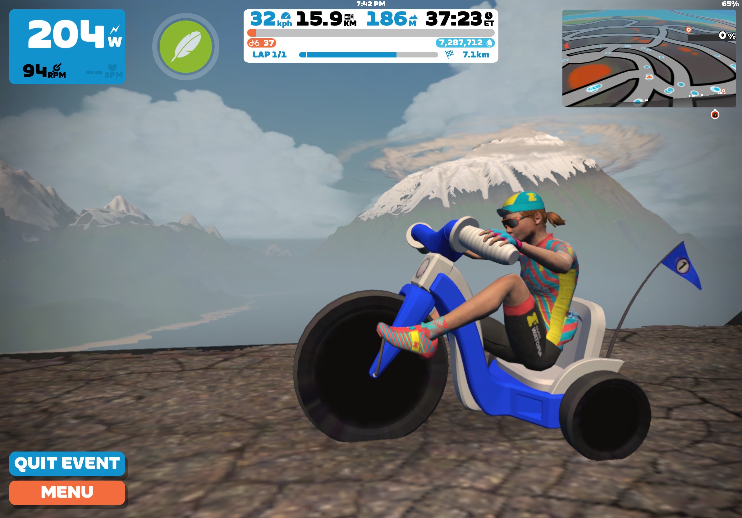 Screenshot of the virtual cycling game Zwift. The rider is shown pedalling a comically oversized tricycle with a virtual mountain range in the background. 